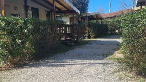 A gravel pathway leading to a building with a covered porch and a statue in the background. - Mobile Home Roma, Camping Paradiso, Viareggio, (Viareggio)