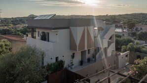 A modern building with a flat roof, solar panels, and a staircase leading to a rooftop terrace.