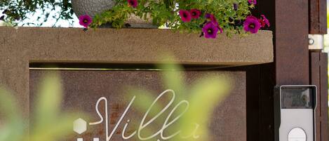A sign for Villa Ilma Luxury with a potted plant above it.