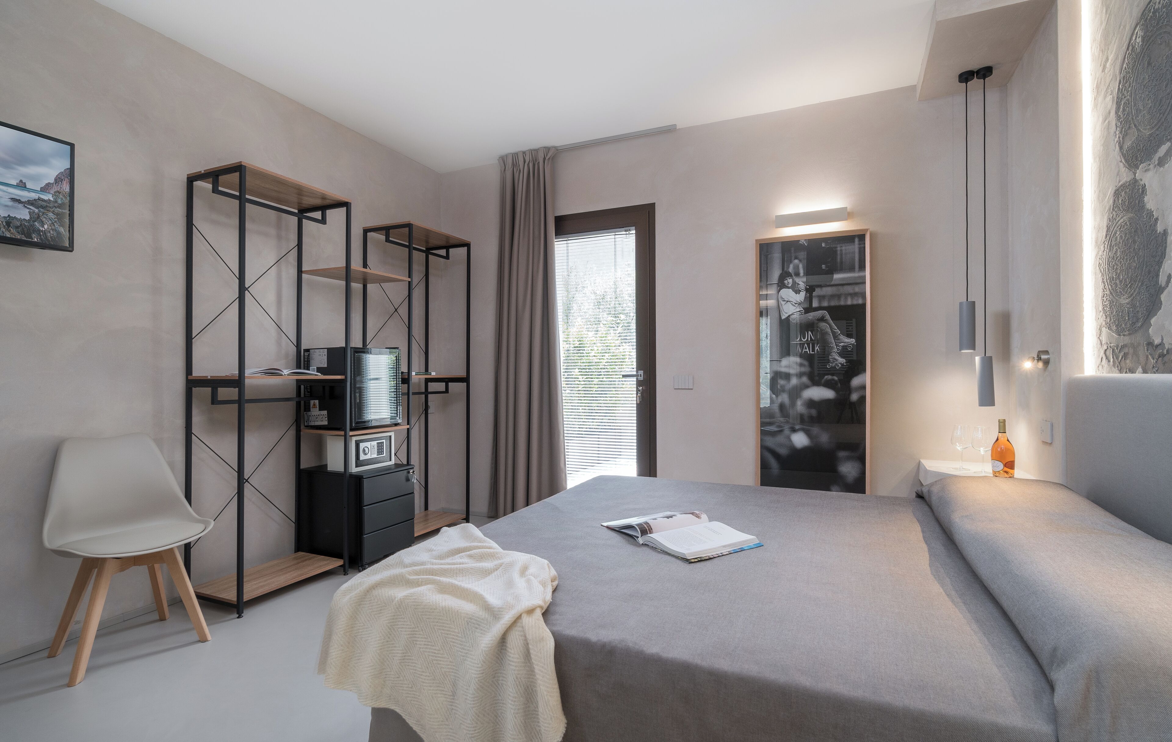 Un dormitorio moderno con cama, una silla, escritorio con computadora y armario.