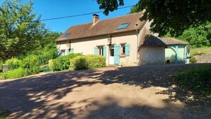 Une maison avec un toit en pente, une petite dépendance attenante et une allée pavée.