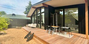 A modern house with a wooden deck, outdoor seating, and large glass doors. - KARUIZAWAHOUSE VILLA (Karuizawa)