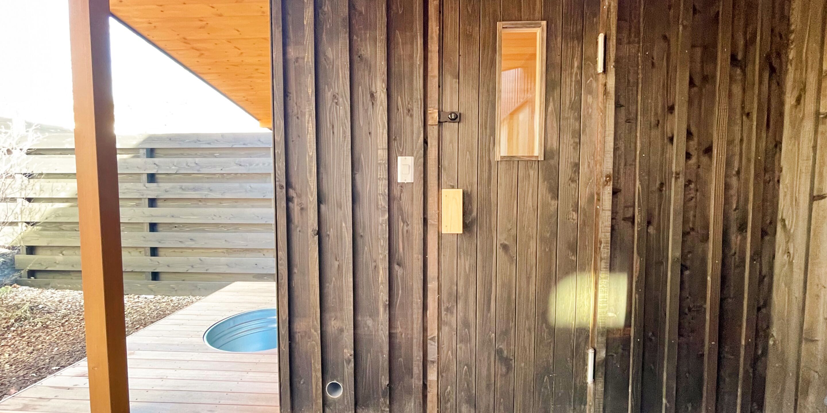 A wooden door with a small window, a metal handle, and a peephole.