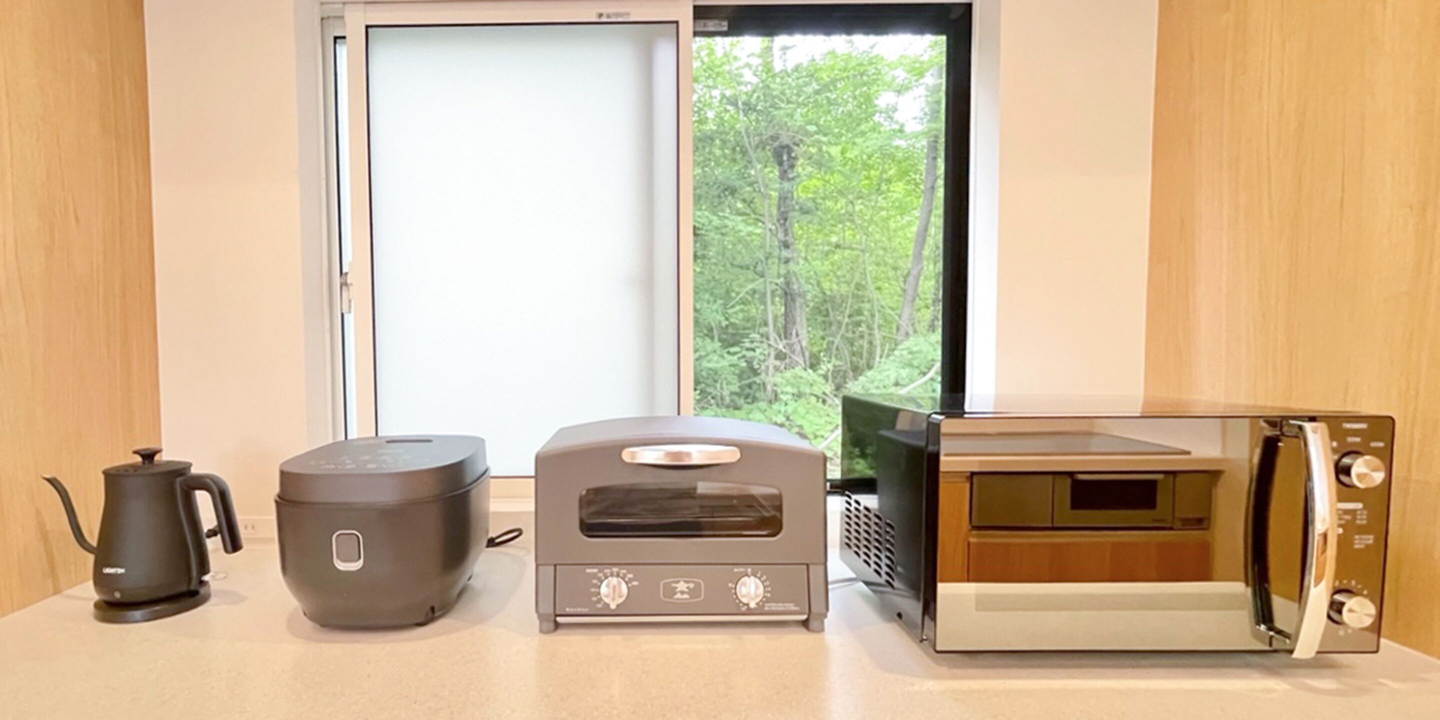 A kitchenette with a coffee maker, rice cooker, and microwave.