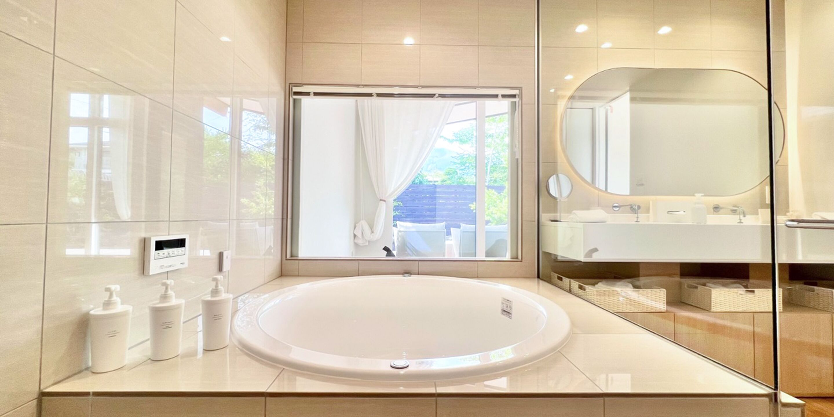 Een moderne badkamer met een groot ovaal wastafel, een douchecabine van glas en een grote spiegel.
