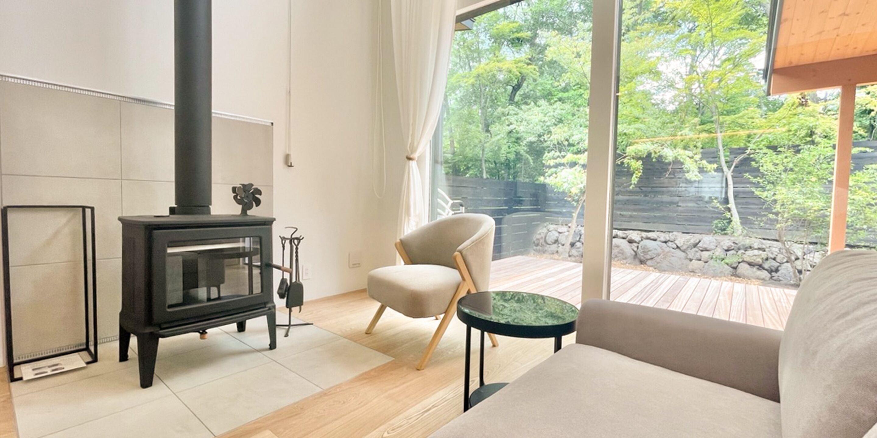 Un salon moderne avec un poêle à bois, un canapé confortable, un fauteuil et une petite table.