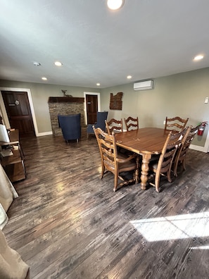 A dining area with a wooden table and chairs, a stone fireplace, and a ceiling with recessed lighting. - The Rellik House and Winery (Central Point)