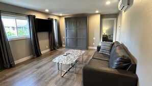A spacious living area with a dark leather sofa, a stone-topped coffee table, and a grey wardrobe. - The Rellik House and Winery (Central Point)