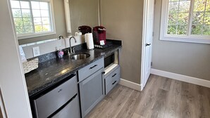 A modern kitchen with a built-in sink, stainless steel appliances, and a window with a view of trees. - The Rellik House and Winery (Central Point)