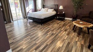 A modern hotel room with a large bed, wooden flooring, a potted plant, and a small side table. - The Rellik House and Winery (Central Point)