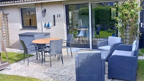 A house with a patio area featuring a table and chairs, a small garden, and a number '23' on the wall. - Idyllic, detached vacation home on the Grevelingenmeer (Herkingen)