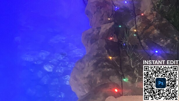 En pool med en vattenfallsanordning och ljusslingor.