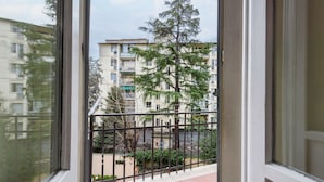 A balcony with a view of a multi-story building, a metal fence, and some greenery. - Fabbroni 3 bedrooms by Mmega (Florence)