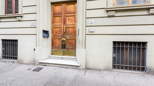A double wooden door with a small step leading up to it, flanked by two barred windows and a number plate indicating the address. - Fabbroni 3 bedrooms by Mmega (Florence)