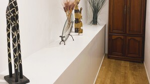 Una recepción con una escultura de jirafa, un jarrón con forma de gato y una planta alta. Se observa un mueble de madera en la esquina.