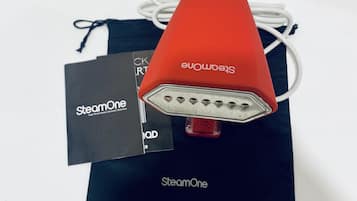 Un altaveu portàtil vermell amb un cable de càrrega blanc i una bossa negra amb el nom de marca "SteamOne" visible.