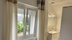 Un bagno moderno con una grande finestra, un lavandino bianco e uno specchio.