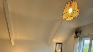 Una camera da letto con un letto grande, un comodino con una lampada, una cassettiera e una finestra con tende.