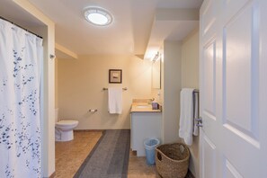A bathroom with a toilet, sink, shower curtain, and a small framed picture on the wall. - Condo Room 300 Grand Victorian's Largest Rental! (Old Orchard Beach)