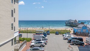 Un hotel frente a la playa con estacionamiento, vistas a la playa y un muelle.
