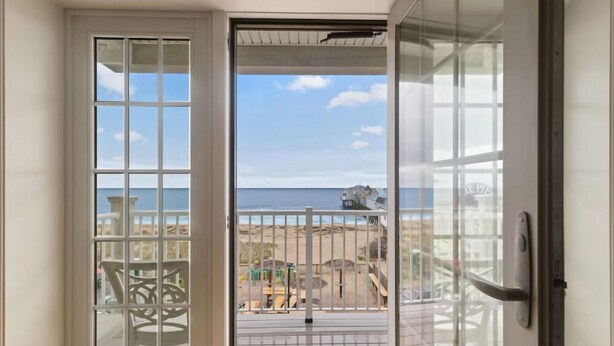 A room with a view of the beach and ocean through a glass door. - Direct Ocean Front Unit With Private Balcony. (Old Orchard Beach)