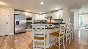 A modern kitchen with white cabinets, stainless steel appliances, and a central island with bar stools.