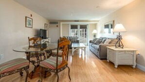 A living room with a dining table, chairs, a sofa, and a lamp.