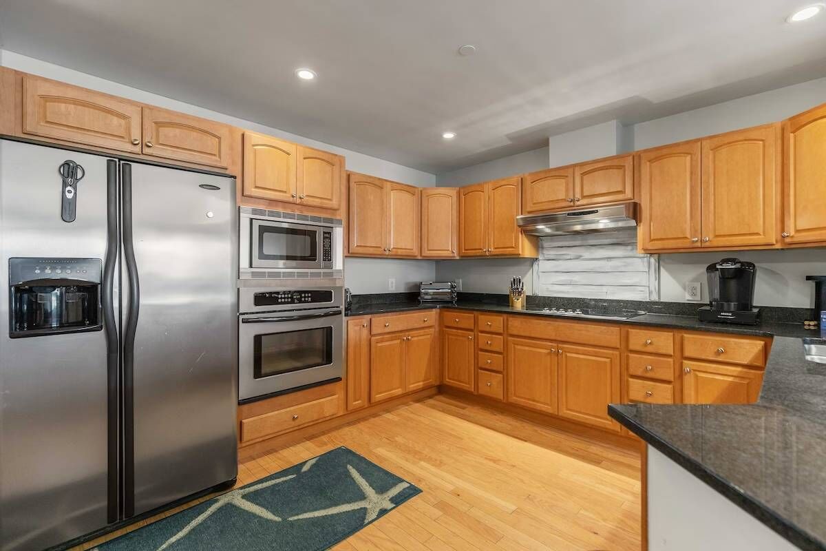 A modern kitchen with wooden cabinets, stainless steel appliances, and a granite countertop.