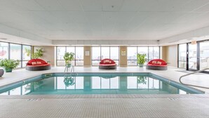 An indoor swimming pool with three red cushioned seating areas around it. - Grand Victorian unit 511 (Old Orchard Beach)