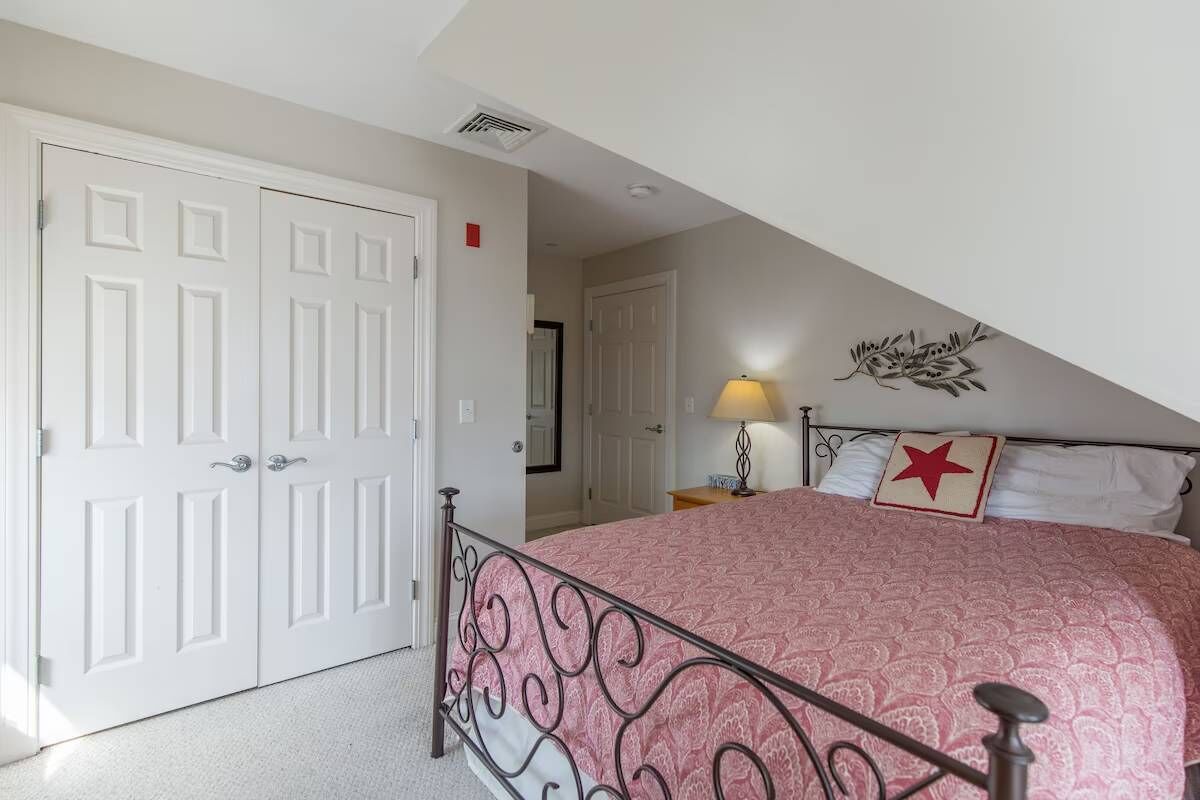 Une chambre à coucher avec un lit, une table de chevet, une lampe, une porte et un élément décoratif mural.