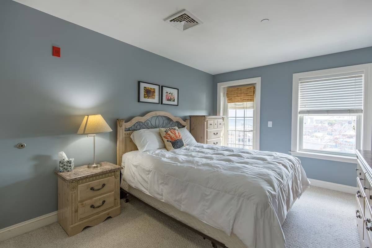Une chambre à coucher avec un lit, une table de chevet, une lampe et une commode.