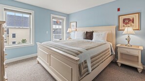 Une chambre à coucher avec un grand lit, deux tables de chevet, une fenêtre et une porte.
