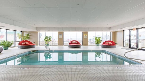 Une piscine intérieure entourée de trois espaces de détente avec des sièges rembourrés de couleur rouge.