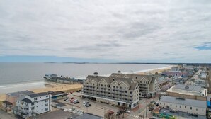 Un hôtel en bord de mer, avec plusieurs étages, une vue sur la plage et une jetée en arrière-plan.