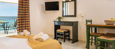 A hotel room with a bed, a desk with a chair, a television, and a balcony with a view.