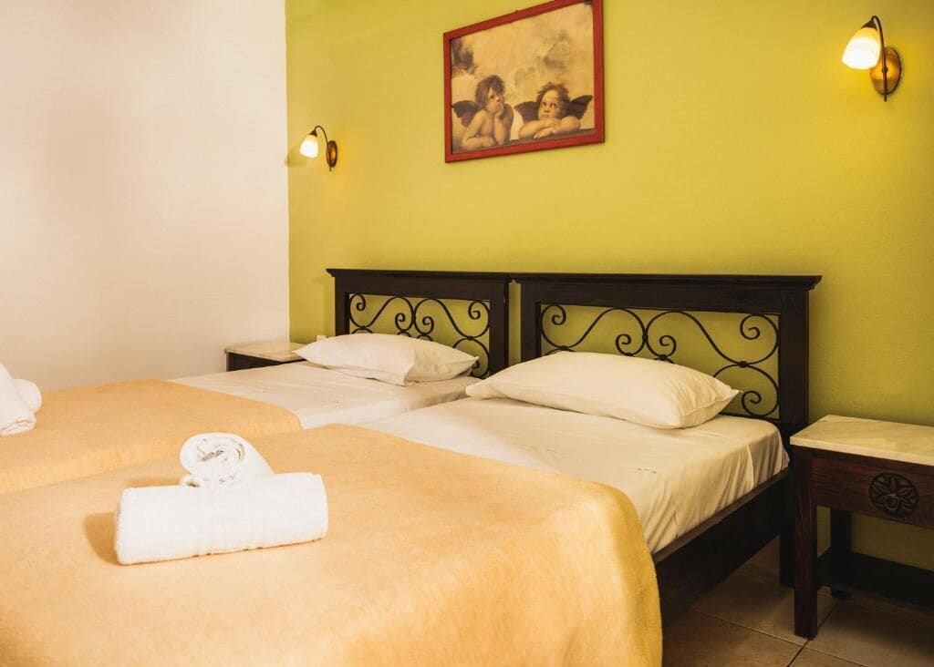 A double bed with a headboard, a bedside table, a wall-mounted light, and a framed picture on the wall.