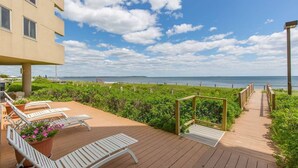 A wooden deck with lounge chairs and a pathway leading to a beach. - Oceanfront Seawatch Condo unit 402 (Old Orchard Beach)