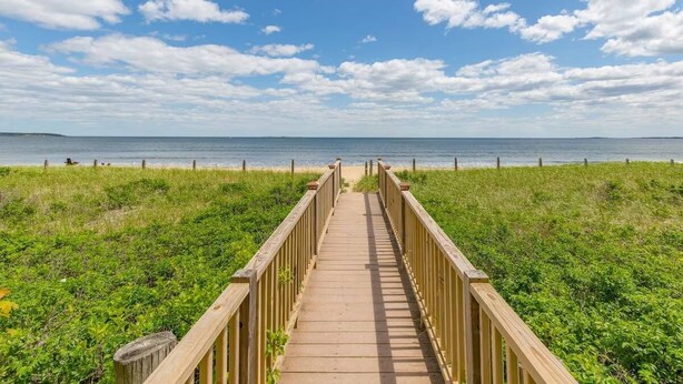 A wooden boardwalk leading to a beach with a clear sky and calm sea. - Oceanfront Seawatch Condo unit 402 (Old Orchard Beach)