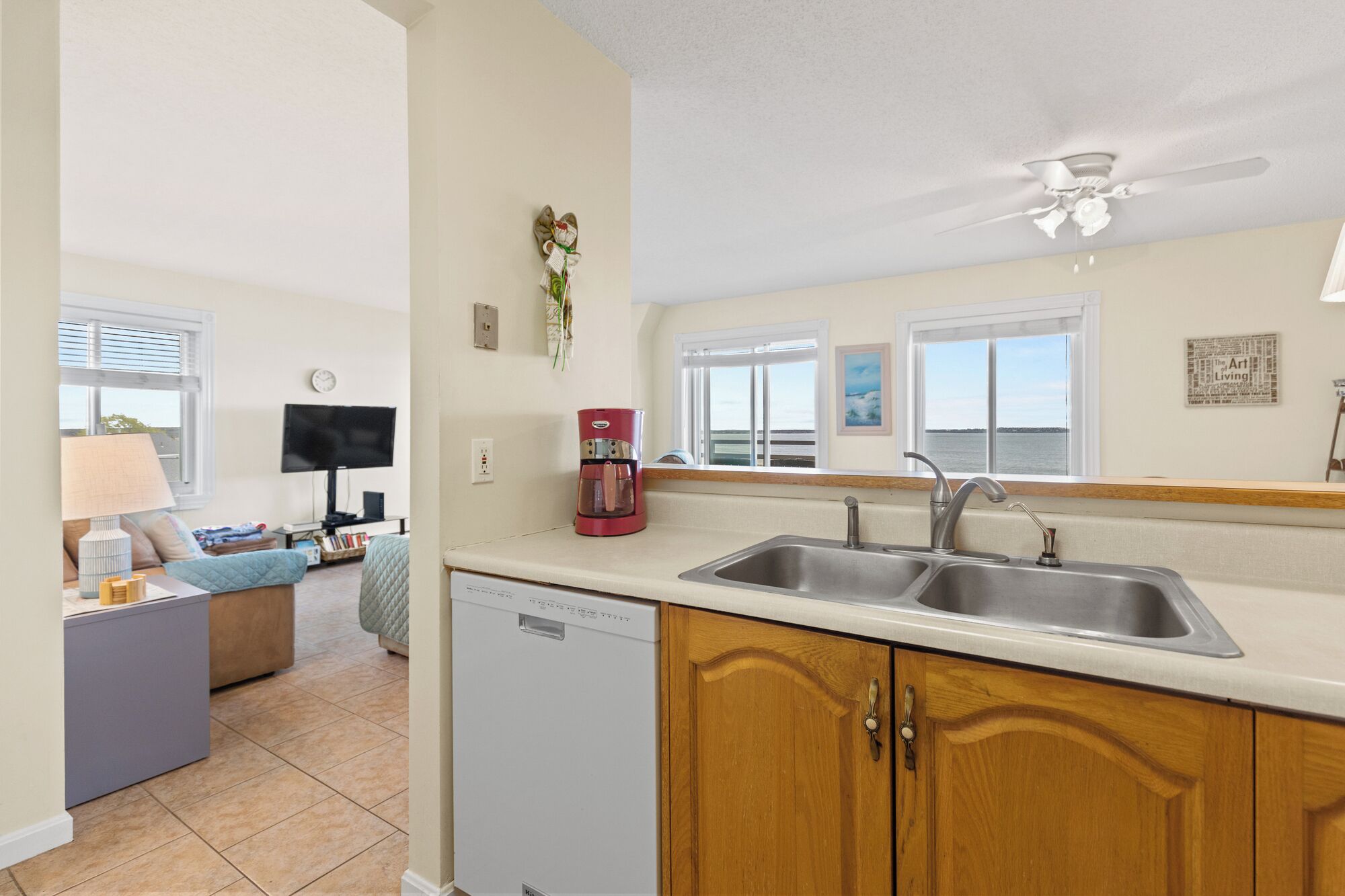 A compact kitchen with a dishwasher, double sink, and a ceiling fan.