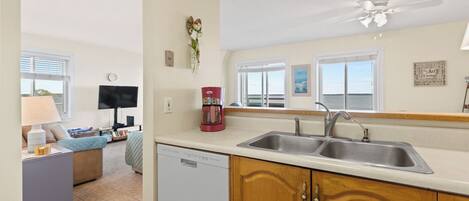 A compact kitchen with a dishwasher, double sink, and a ceiling fan.