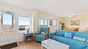 A living room with a sofa, a coffee table, and a chair. There is a window with a view of the beach. - Oceanfront Seawatch Condo unit 402 (Old Orchard Beach)