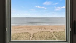 Vista a la playa a través de una ventana con cielo despejado.