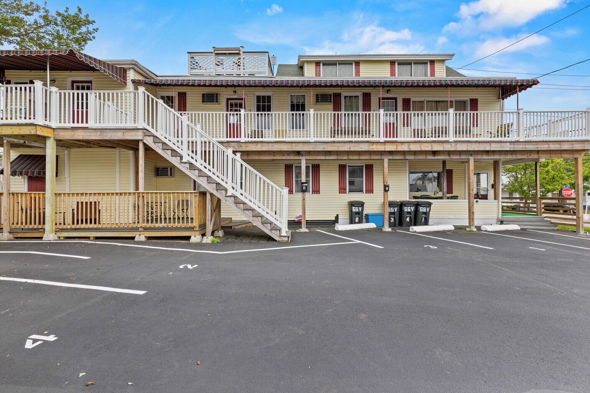 A two-story motel with a covered front porch, a staircase to the upper level, and a parking lot.