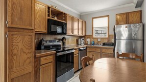 A kitchen with wooden cabinets, a stainless steel refrigerator, a microwave, an oven, and a dining table with chairs. - Seaside Village Condo #3- 300 ft to Sandy Beaches! (Old Orchard Beach)
