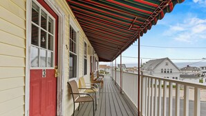 A wooden deck with a red door and a striped awning, overlooking a residential area. - Seaside Village Condo #3- 300 ft to Sandy Beaches! (Old Orchard Beach)