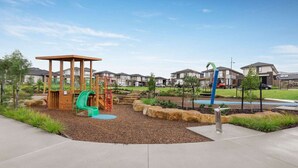 A playground with a wooden play structure, a slide, and a climbing area. - StayAU 4BR Designer Home in Knox (Wantirna South)