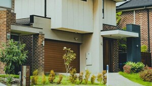 A modern two-story house with a flat roof, large windows, and a brick facade. - StayAU 4BR Designer Home in Knox (Wantirna South)