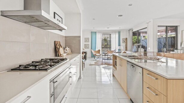 A modern kitchen with a central island, stainless steel appliances, and a view to the backyard. - StayAU 4BR Designer Home in Knox (Wantirna South)