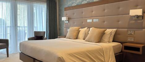 A modern hotel bedroom with a large bed, a nightstand, and a chair.