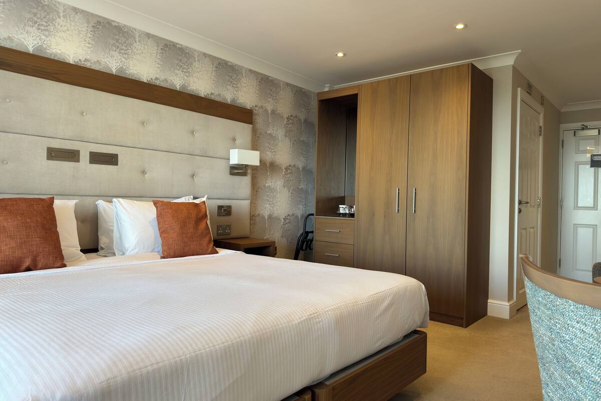 Une chambre à coucher avec un grand lit, une armoire en bois et une table de chevet avec une lampe.